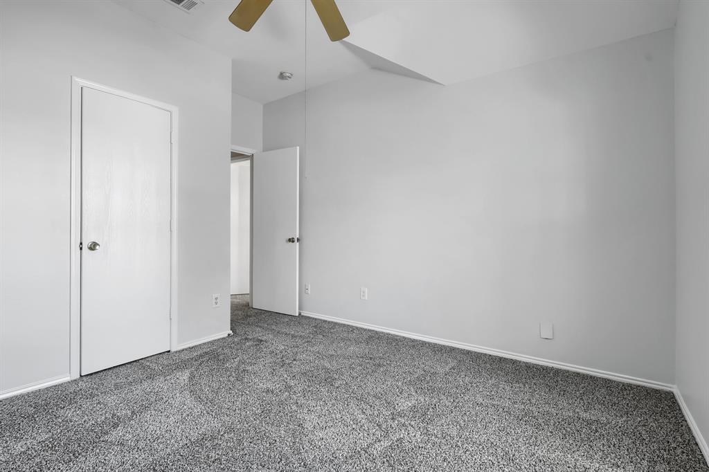 Neutral interior featuring wall-to-wall carpeting, vaulted ceiling, and a ceiling fan
