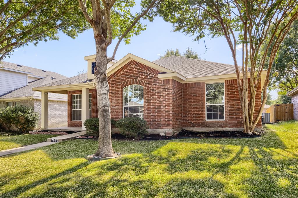 Brick exterior featuring a gabled roofline, arched window detailing, a covered front porch with support columns, and mature landscaping