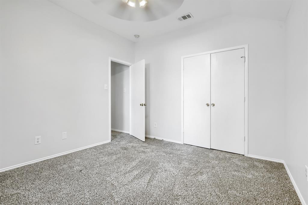 Interior space featuring neutral wall tones, plush wall-to-wall carpeting, a multi-pane window, and a central ceiling fan with integrated lighting