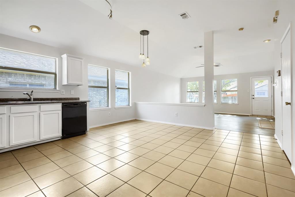 Kitchen featuring white shaker-style cabinetry, dark stone-finish countertops, tile flooring, and multi-light pendant fixtures