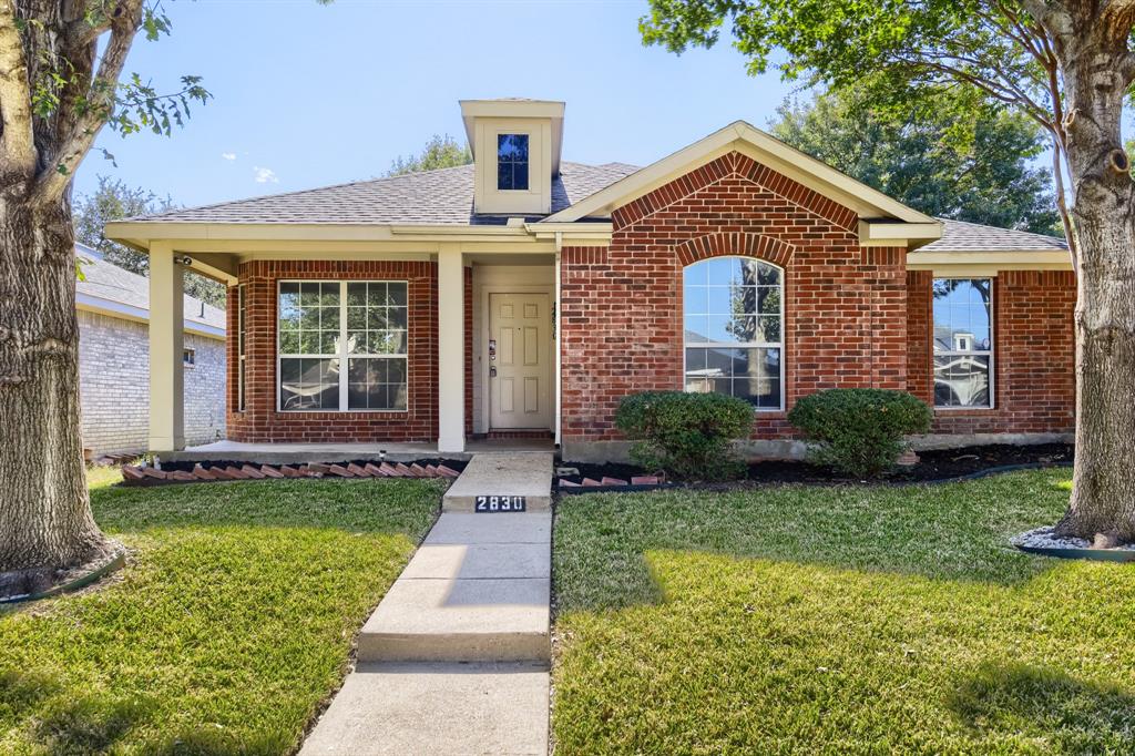 Traditional brick exterior featuring a covered front porch, arched window detailing, a central dormer, and a concrete walkway