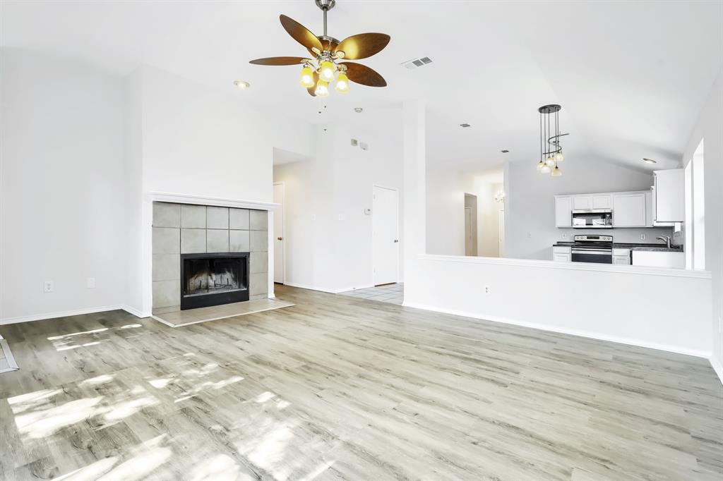 Vaulted ceilings, wood-finish flooring, tile-surround fireplace, and ceiling fan with integrated lighting
