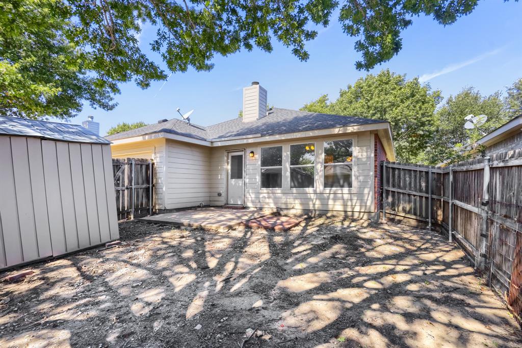 Room featuring wood-finish flooring, vaulted ceilings, multi-pane windows, and a ceiling fan, with double doors opening to a tiled entrance area