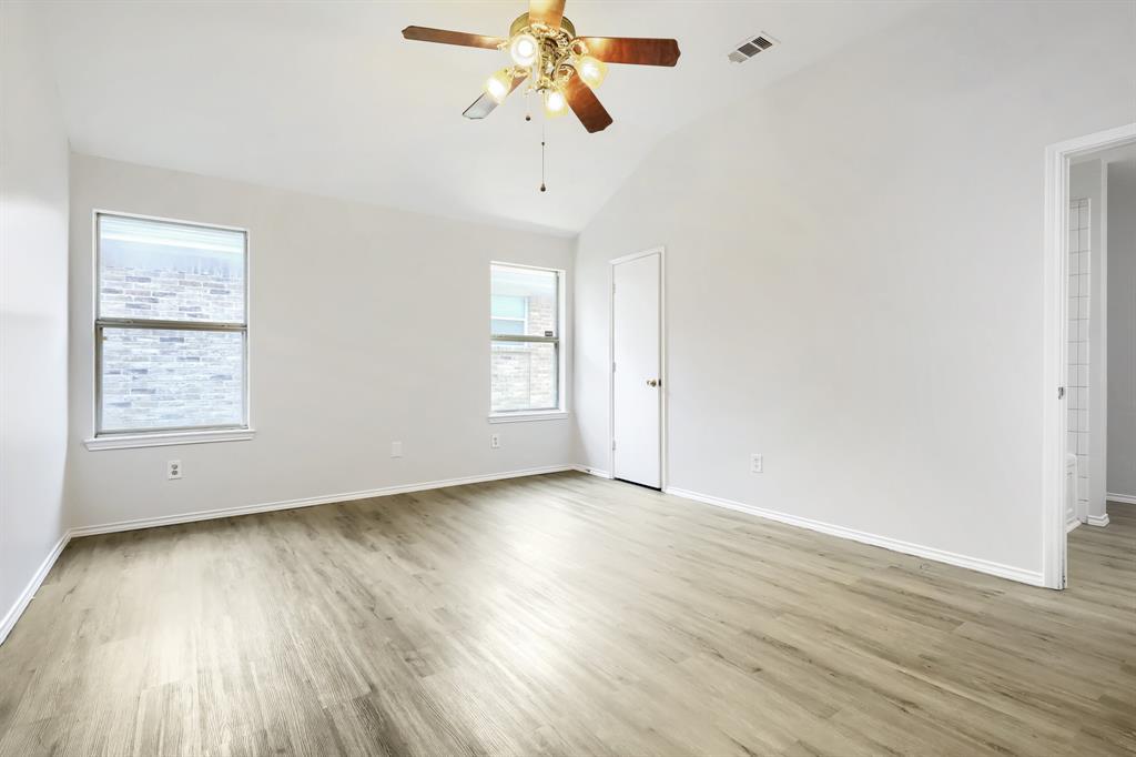 Neutral interior room featuring wood-finish flooring, high ceilings, and a central ceiling fan with multi-light fixture
