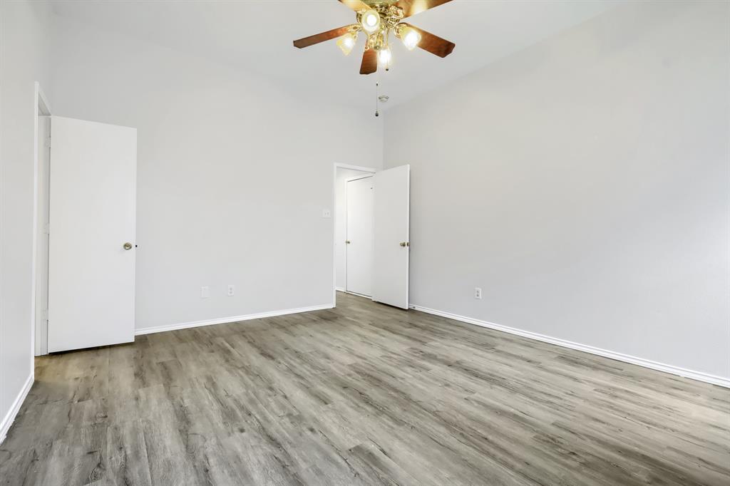 White vanity featuring a rectangular integrated sink, brushed-metal hardware, wood-finish flooring, and a shower-tub combination with white tile surround