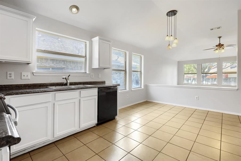 Kitchen featuring white shaker-style cabinetry, stone-finish countertops, stainless steel appliances, ceramic tile flooring, and vaulted ceilings
