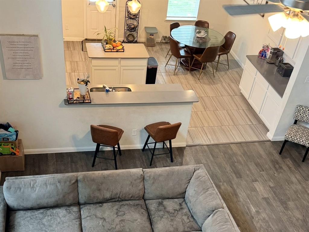 Kitchen featuring white cabinetry, neutral-toned countertops, a central island with an integrated sink, and tile flooring