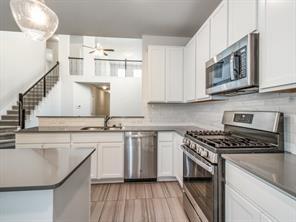 Kitchen featuring white shaker cabinetry, stainless steel appliances, neutral stone-finish countertops, and wood-finish flooring