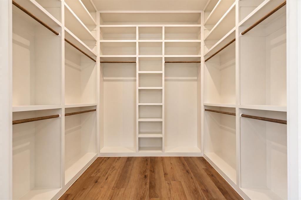 Built-in closet system with multiple shelving units, hanging rods, and wood-finish flooring