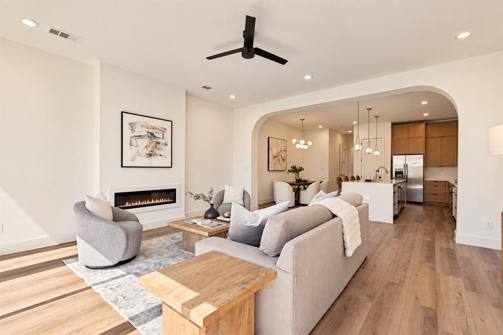 Recessed lighting, wood-finish flooring, a modern linear fireplace, a ceiling fan, and an arched entryway