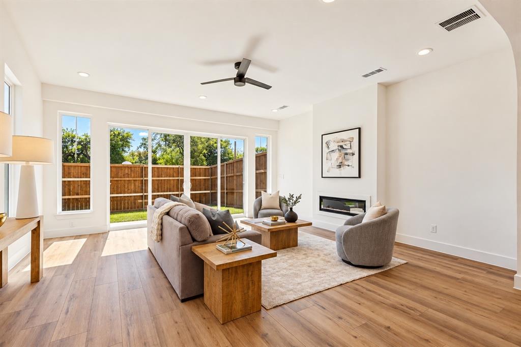 Open-concept living space with wood-finish flooring, a contemporary fireplace, and recessed lighting