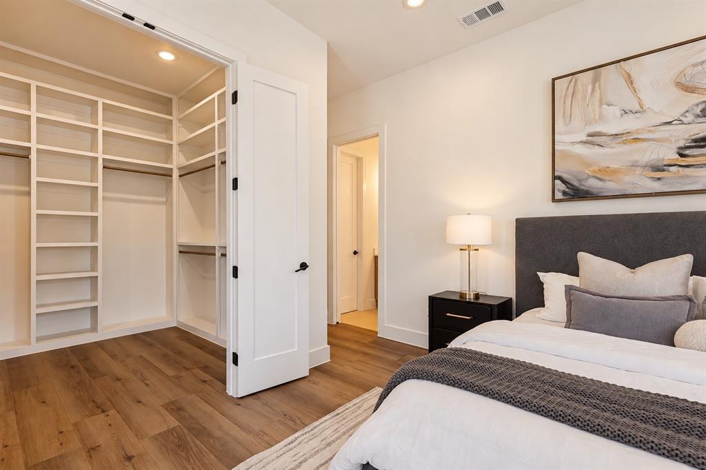Wood-finish flooring, built-in closet shelving, recessed lighting, and a solid core door with matte black hardware
