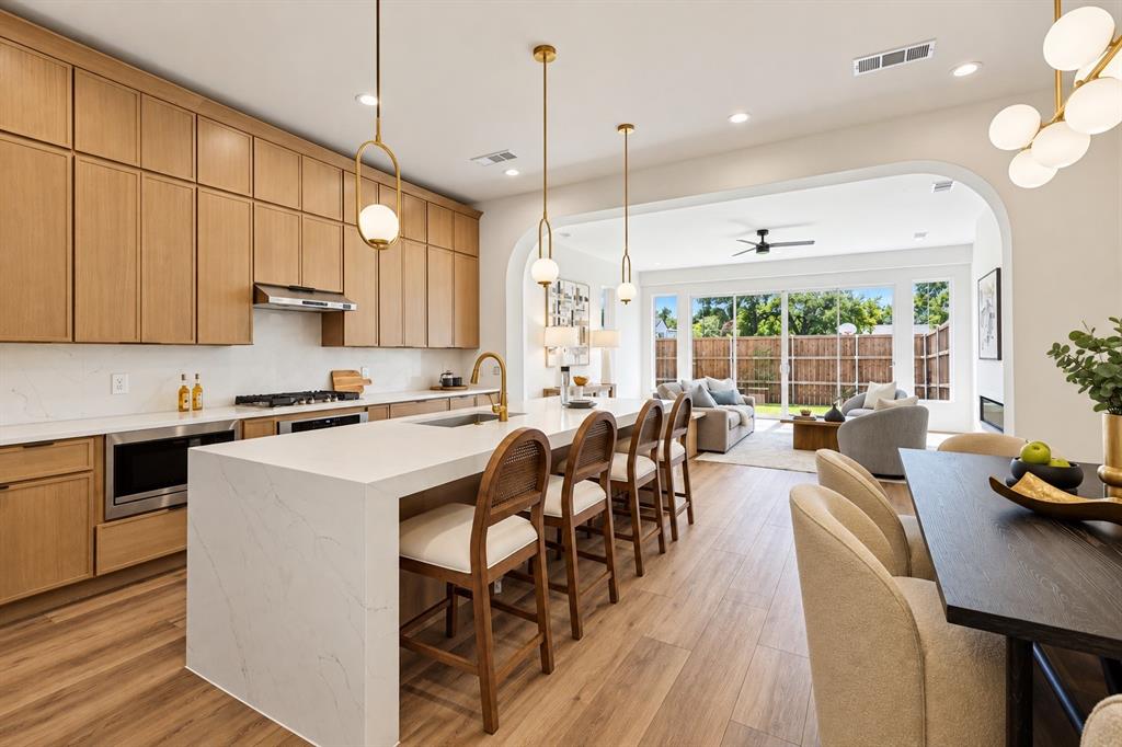 Gourmet kitchen with light wood-finish cabinetry, white countertop surfaces, and stainless steel appliances