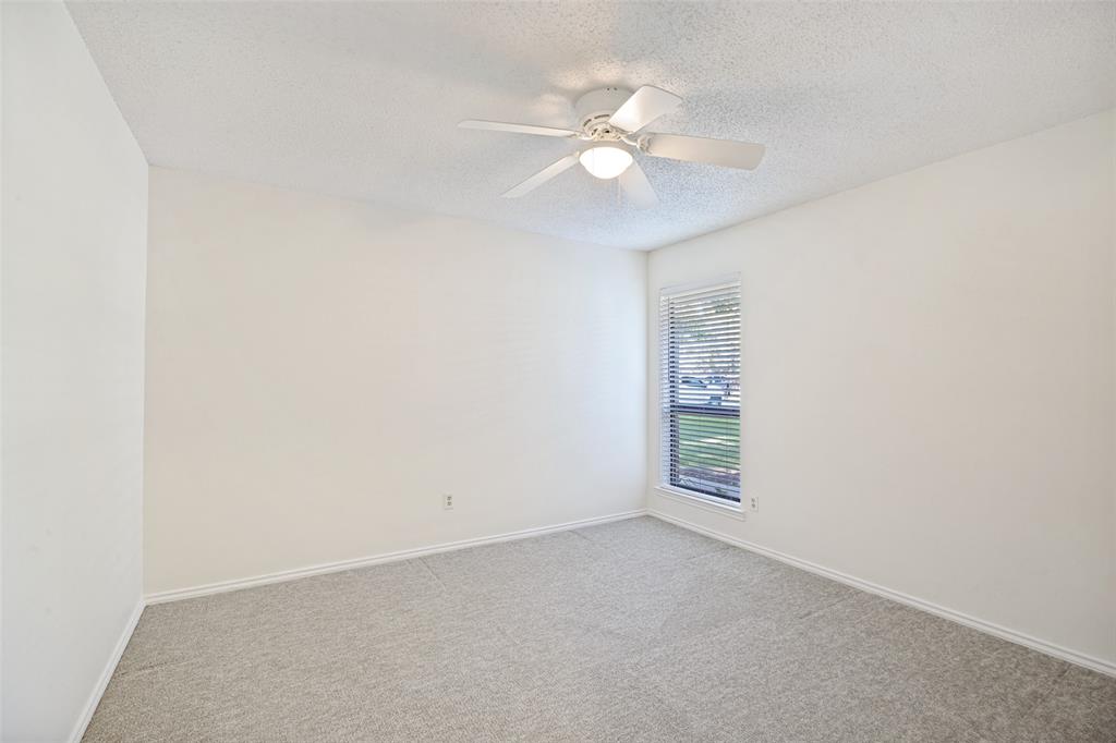 Neutral-toned wall-to-wall carpeting, ceiling fan with integrated lighting, and window with horizontal blinds