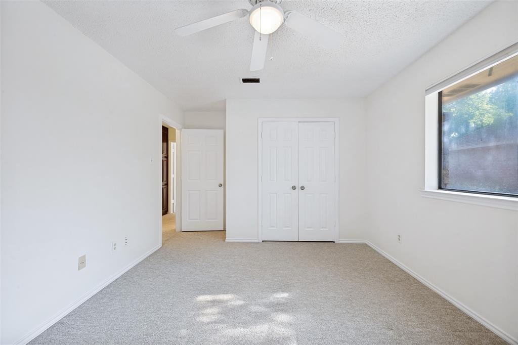 Neutral interior featuring wall-to-wall carpeting, white interior doors, double-door closet, and a ceiling-mounted light fixture with fan