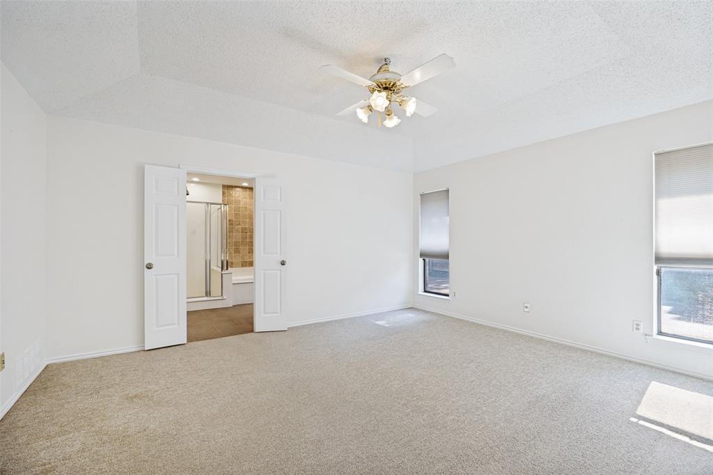 Tray ceiling, central ceiling fan with multi-light fixture, dual interior doors, and dual windows with roller shades