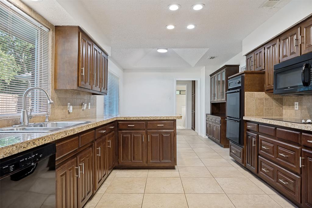 Kitchen featuring dark wood cabinetry, stone countertops, tiled backsplash, integrated double wall ovens, and recessed lighting