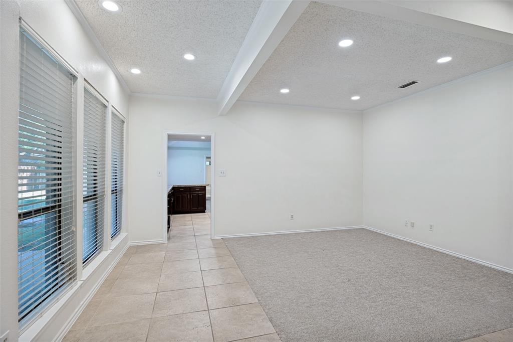 Room featuring recessed lighting, a tray ceiling, large windows with horizontal blinds, neutral carpeting, and tile flooring