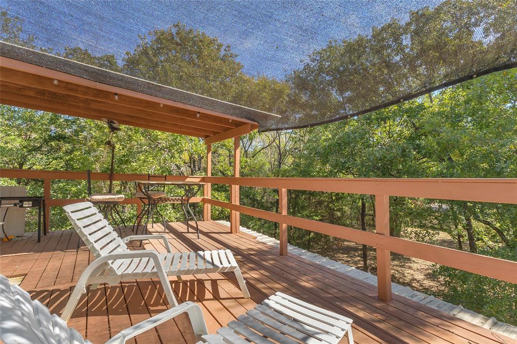 Upper wood deck with covered area, shade sail, and tree views