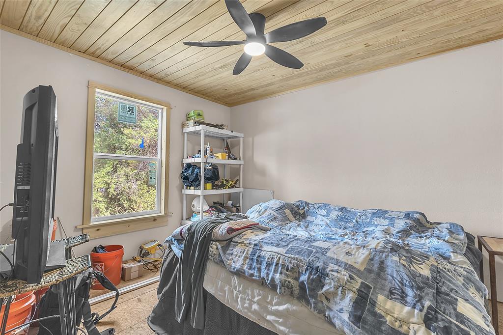 Bedroom with wood plank ceiling, ceiling fan, and window