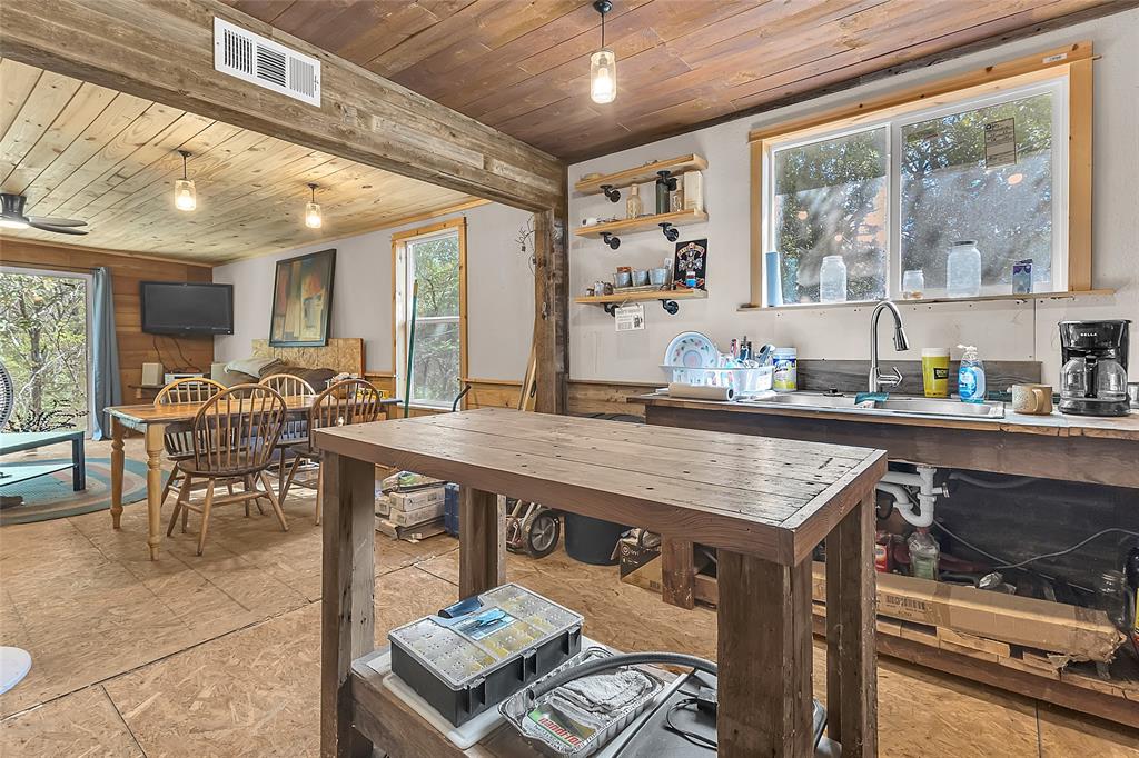 Kitchen sink under window with open shelving and living area beyond