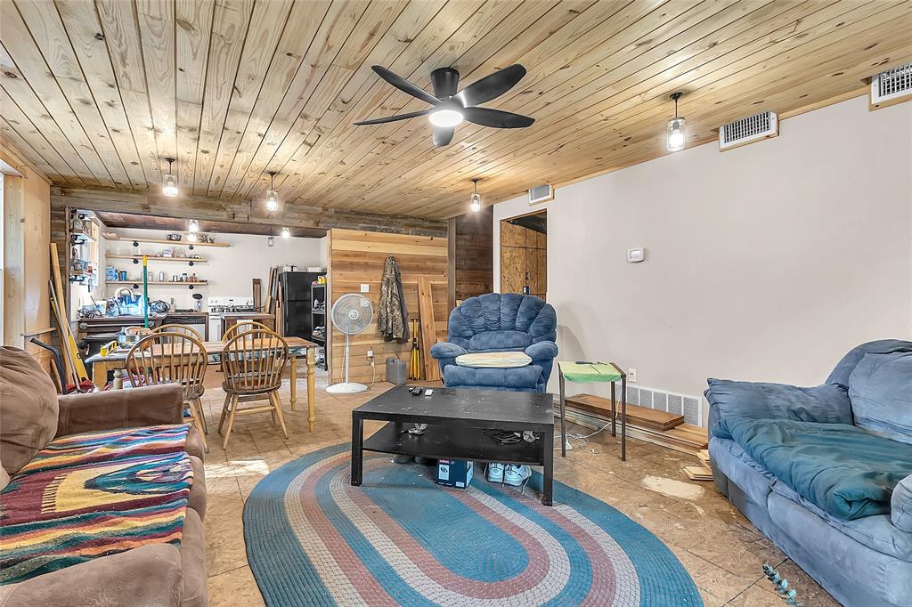 Open living area with wood plank ceiling, ceiling fan, and view to kitchen