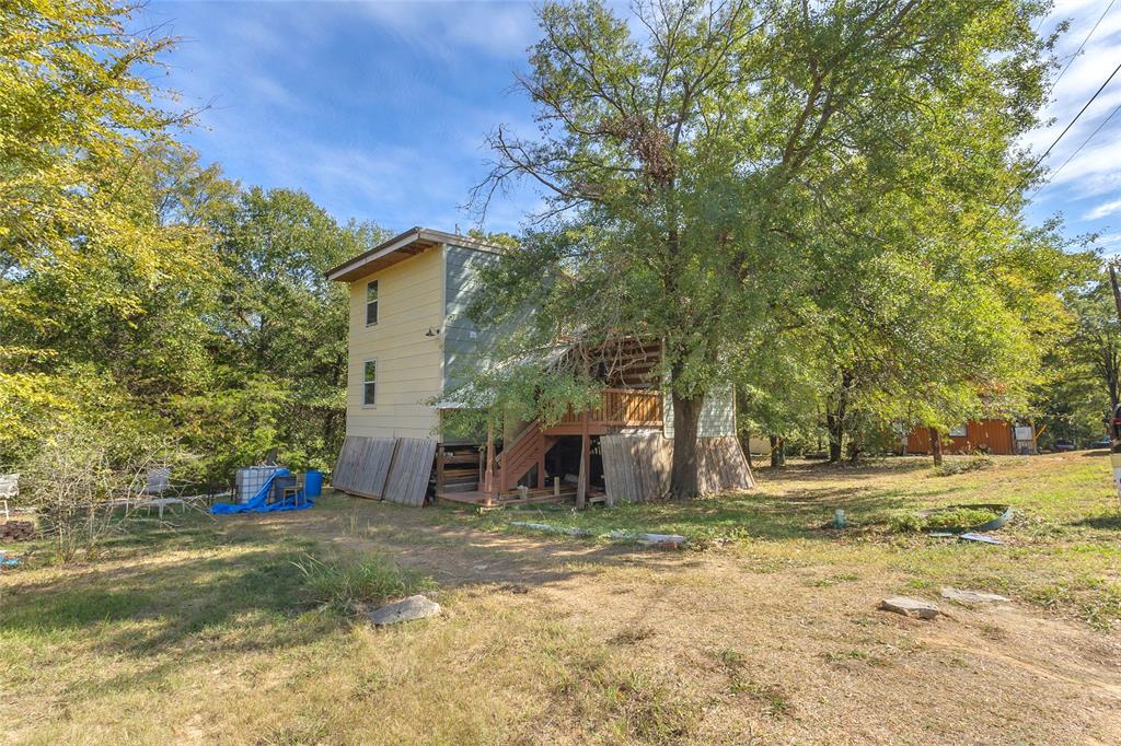 Backyard with large shade tree and stairs to the deck