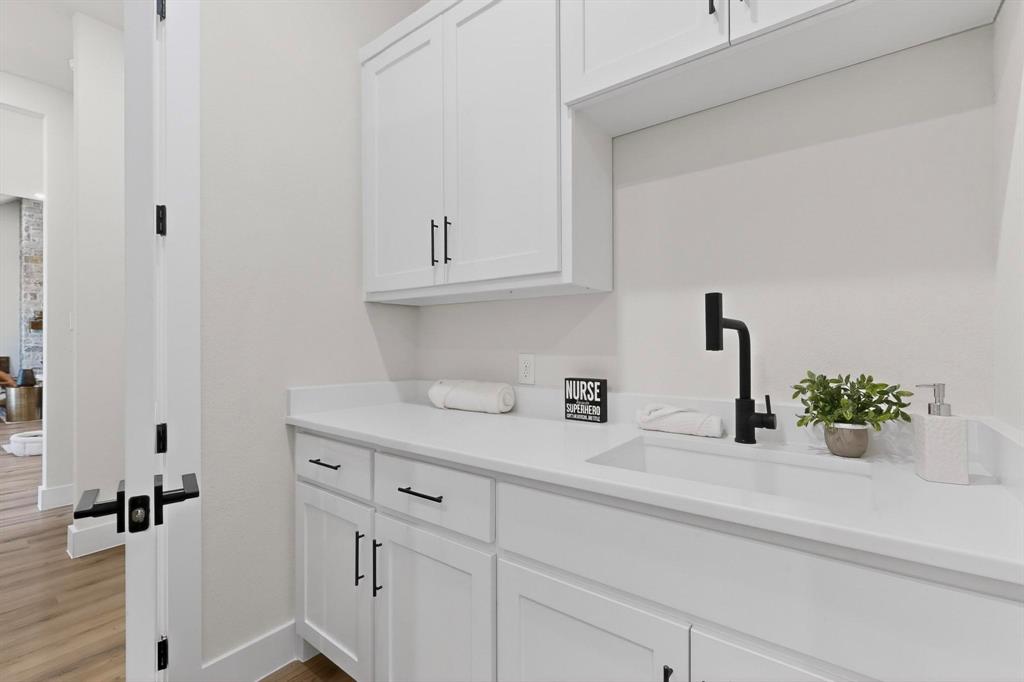 Shaker-style white cabinetry with matte black hardware, stone-surface countertop, integrated rectangular sink, and matte black gooseneck faucet