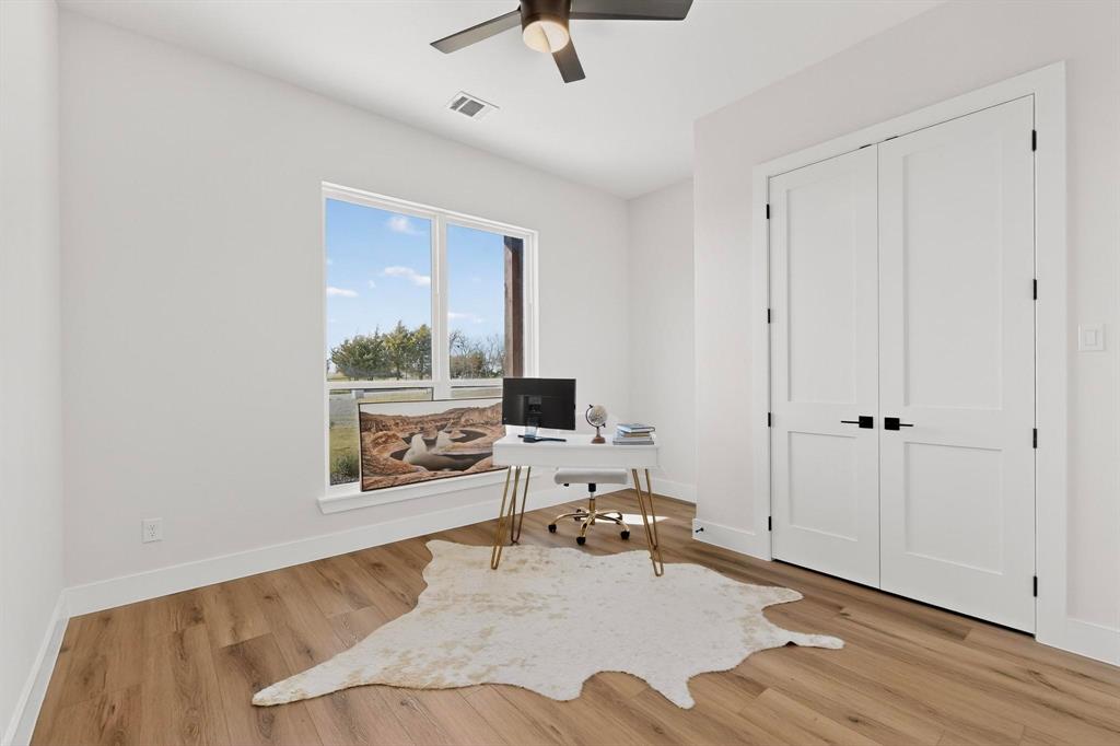 Room featuring wood-finish flooring, white double doors with matte black hardware, and a ceiling fan with integrated lighting