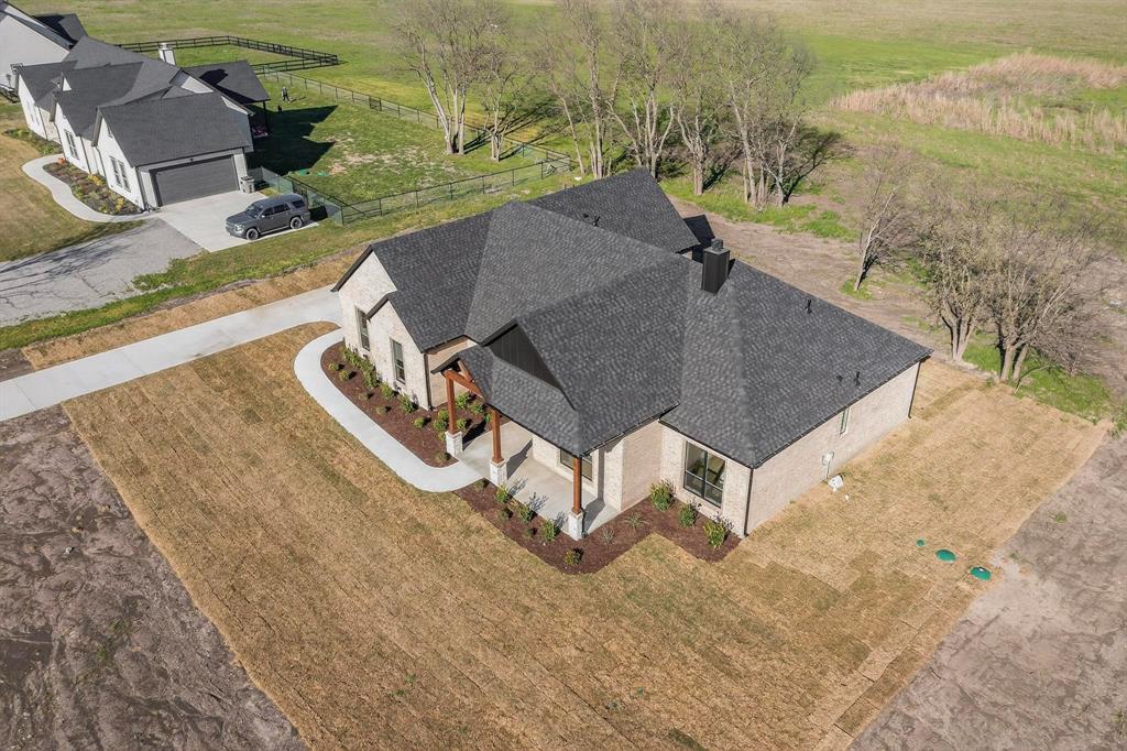 Single-story residence featuring light-toned brick masonry, a multi-gabled asphalt shingle roof, a covered front entryway with timber posts, and a concrete driveway