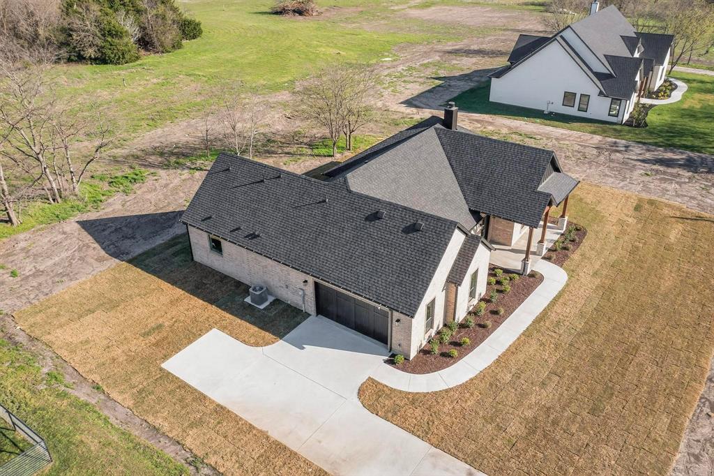 Single-story residence featuring a light-toned masonry exterior, dark asphalt shingle roof, attached garage, and concrete driveway