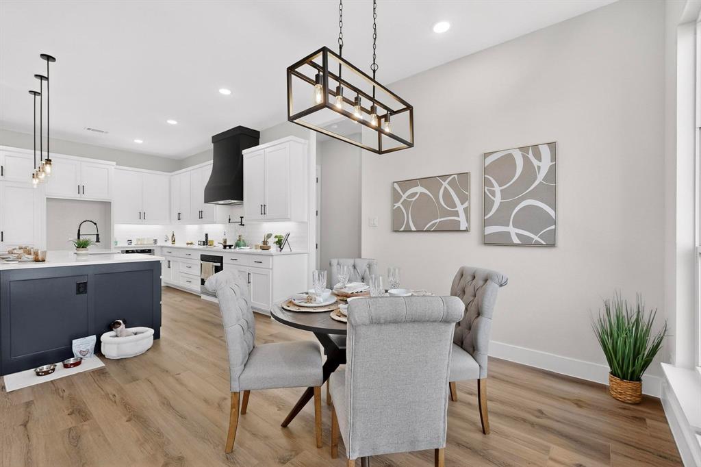 Kitchen featuring an oversized island with dark cabinetry, white perimeter cabinets, custom range hood, recessed lighting, and wood-finish flooring
