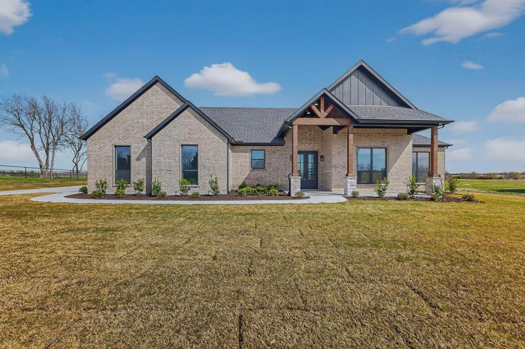 Brick exterior with vertical siding accents, covered front porch featuring timber beam supports, stone column bases, and a multi-gabled roofline