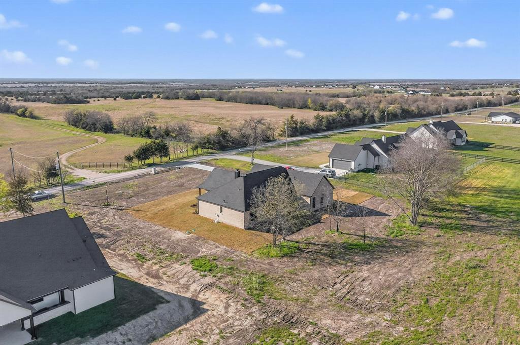 Aerial perspective featuring a multi-gabled roofline, brick exterior, paved driveway, and expansive acreage