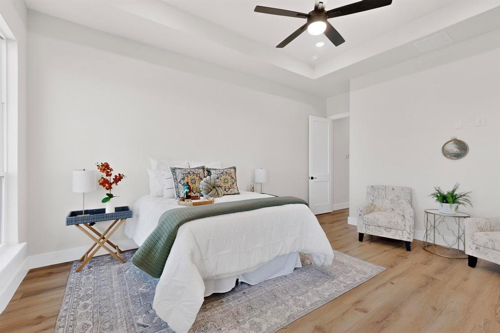 Tray ceiling with recessed lighting, wood-finish flooring, and a central ceiling fan