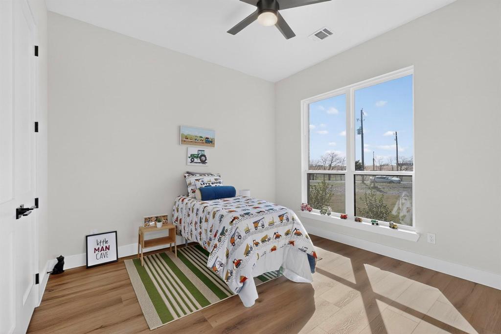 Neutral-toned interior featuring wood-finish flooring, a ceiling fan with integrated lighting, and large windows with a wide ledge