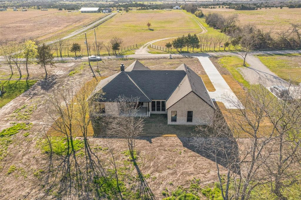 Single-story residence with a brick exterior, multi-gabled roof, covered rear patio, and a concrete driveway on an expansive lot