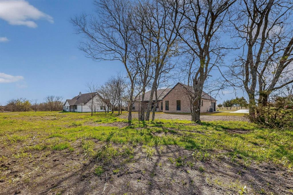 Expansive acreage featuring mature trees, natural landscape, and a multi-structure property with brick and siding exteriors
