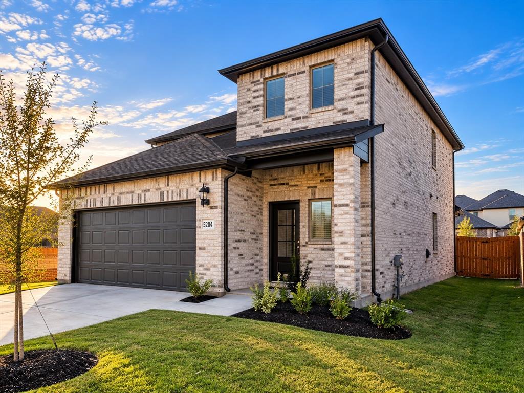 Two-story brick exterior featuring a multi-gabled roofline, integrated two-car garage, and glass-paneled entry door