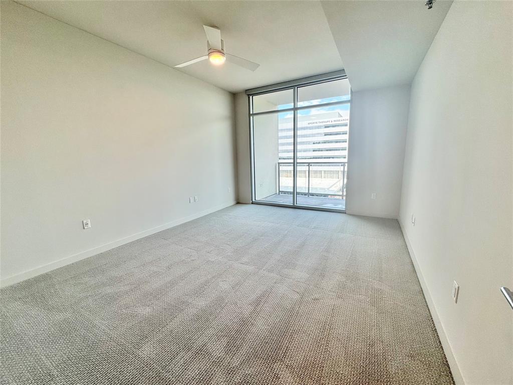 Spare room with light carpet, expansive windows, and ceiling fan