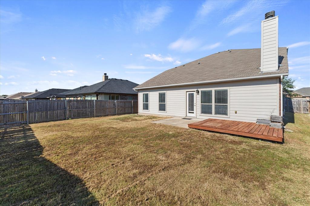 Rear exterior featuring horizontal lap siding, a chimney, a wood deck, a concrete patio, and a wood privacy fence