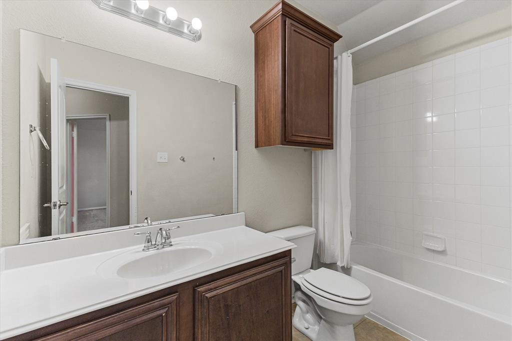 Bathroom featuring dark wood-finish cabinetry, a white countertop with an integrated sink, a wall-mounted storage cabinet, and a shower-tub combination with white tile surround