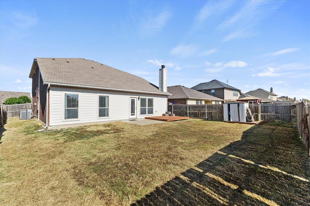 Rear elevation featuring horizontal siding, a masonry chimney, a wood deck, and a wood privacy fence enclosing the yard