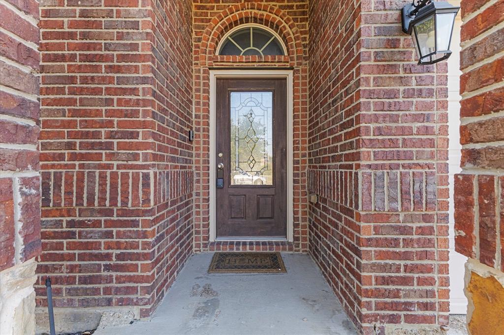 Entryway featuring red brick exterior siding, arched brick detailing with a semi-circular transom window, and a dark-finish wood door with glass inlay Entryway featuring red brick exterior siding, arched brick detailing with a semi-circular transom window, and a dark-finish wood door with glass inlay