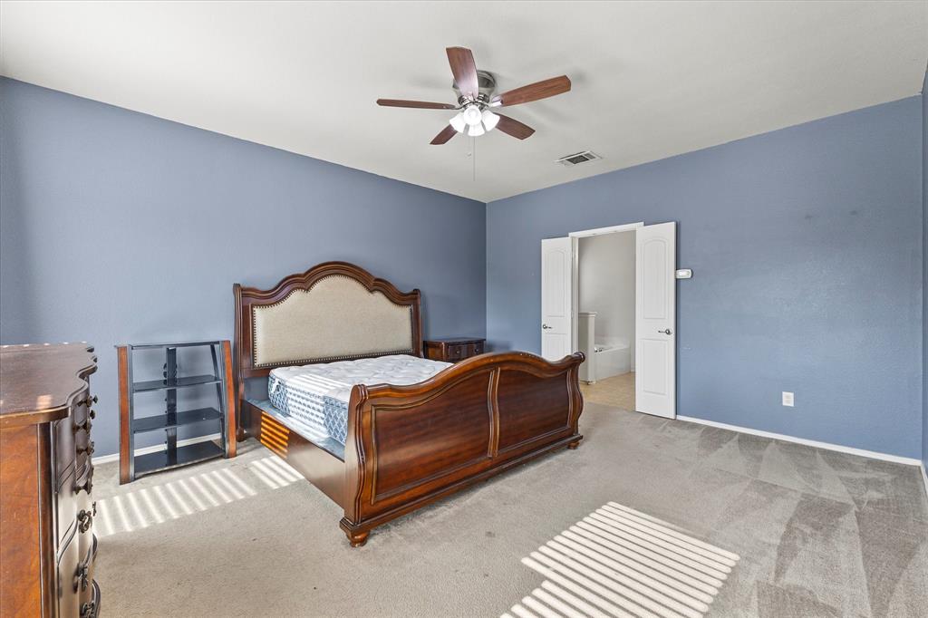Room featuring neutral-toned carpeting, a central ceiling fan with integrated lighting, and double doors