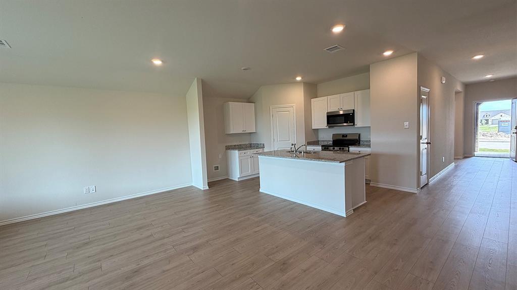 Open-concept living area featuring wood-finish flooring, recessed lighting, and a kitchen island with integrated sink