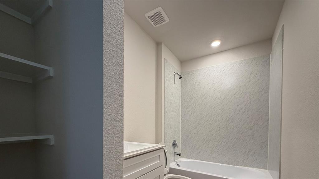 Bathroom featuring a white bathtub, patterned shower surround, and a chrome shower fixture