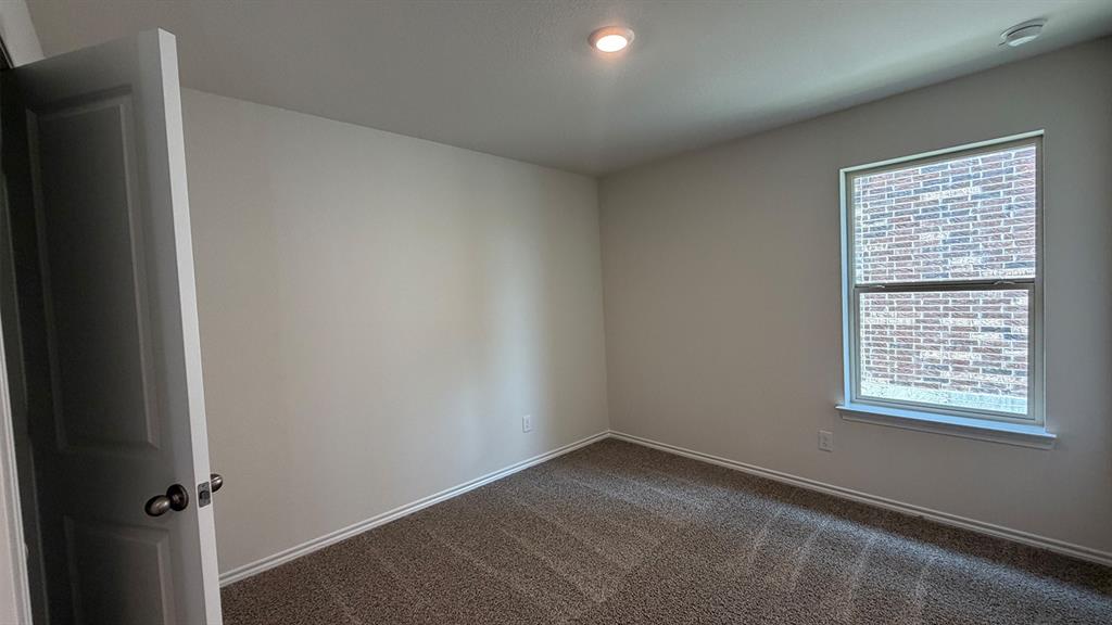 Carpeted room featuring a single window with white trim, a recessed ceiling light, and a white interior door with a dark handle
