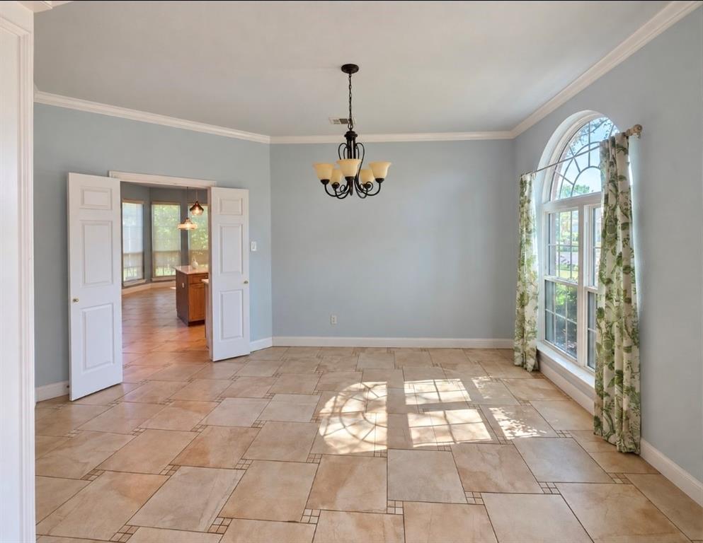 Formal room featuring ceramic tile flooring, arched window with decorative muntins, multi-arm metal chandelier, and double-panel door entry Formal room featuring ceramic tile flooring, arched window with decorative muntins, multi-arm metal chandelier, and double-panel door entry