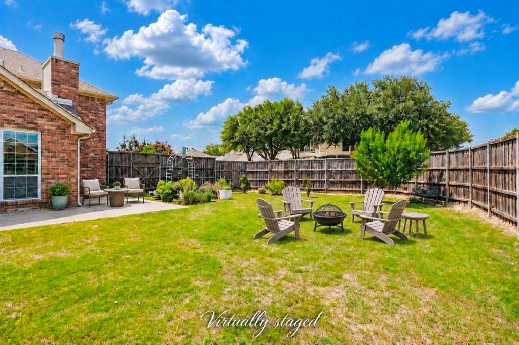 Fenced backyard featuring brick exterior siding, a concrete patio, and mature trees